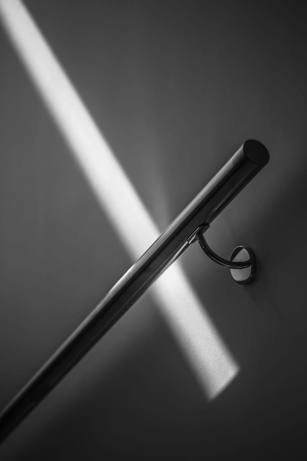 A wall-mounted handrail catching a shaft of light.