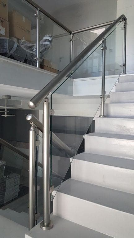 A stainless and glass balustrade on a pale staircase.