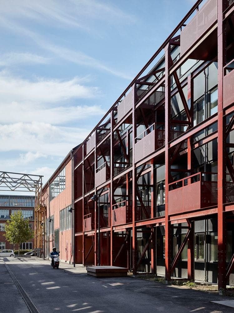 A red steel exoskeleton carrying walkways across a glazed facade.