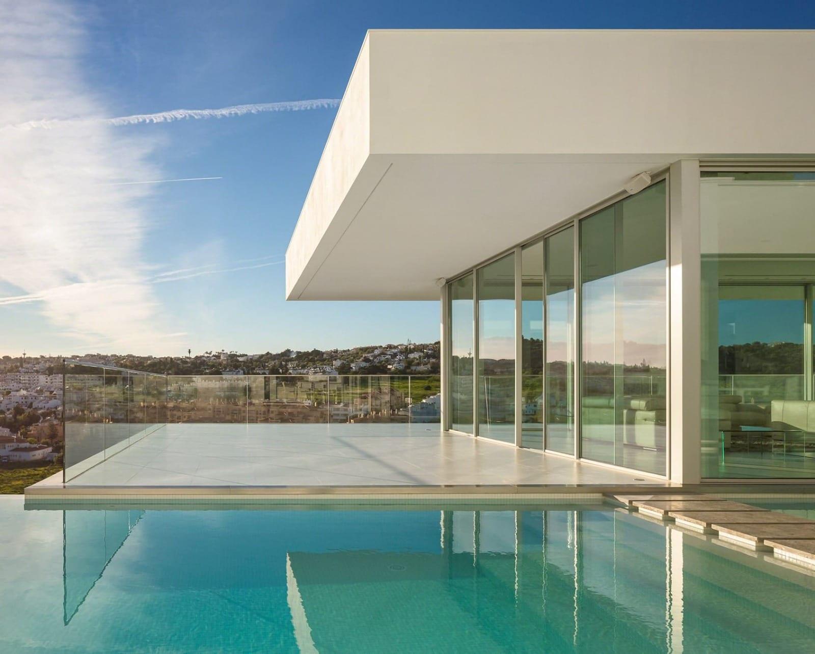 A frameless glass balustrade edging a terrace and pool.