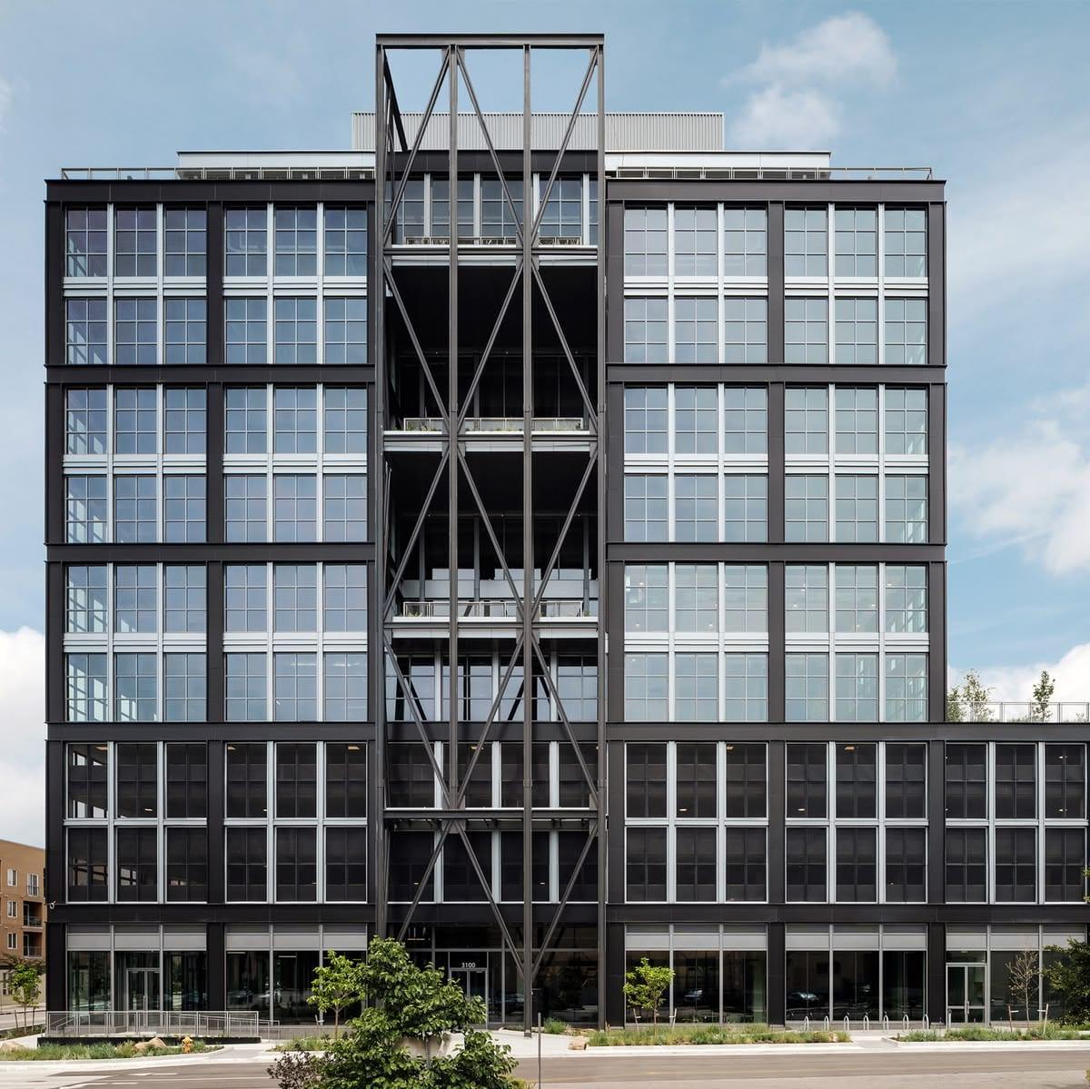 A black steel and glass office building with an expressed braced core.