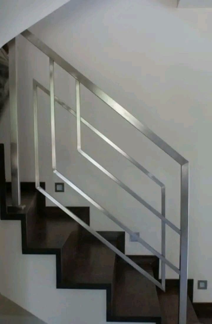 A stainless steel stair railing in a stone-finished interior.